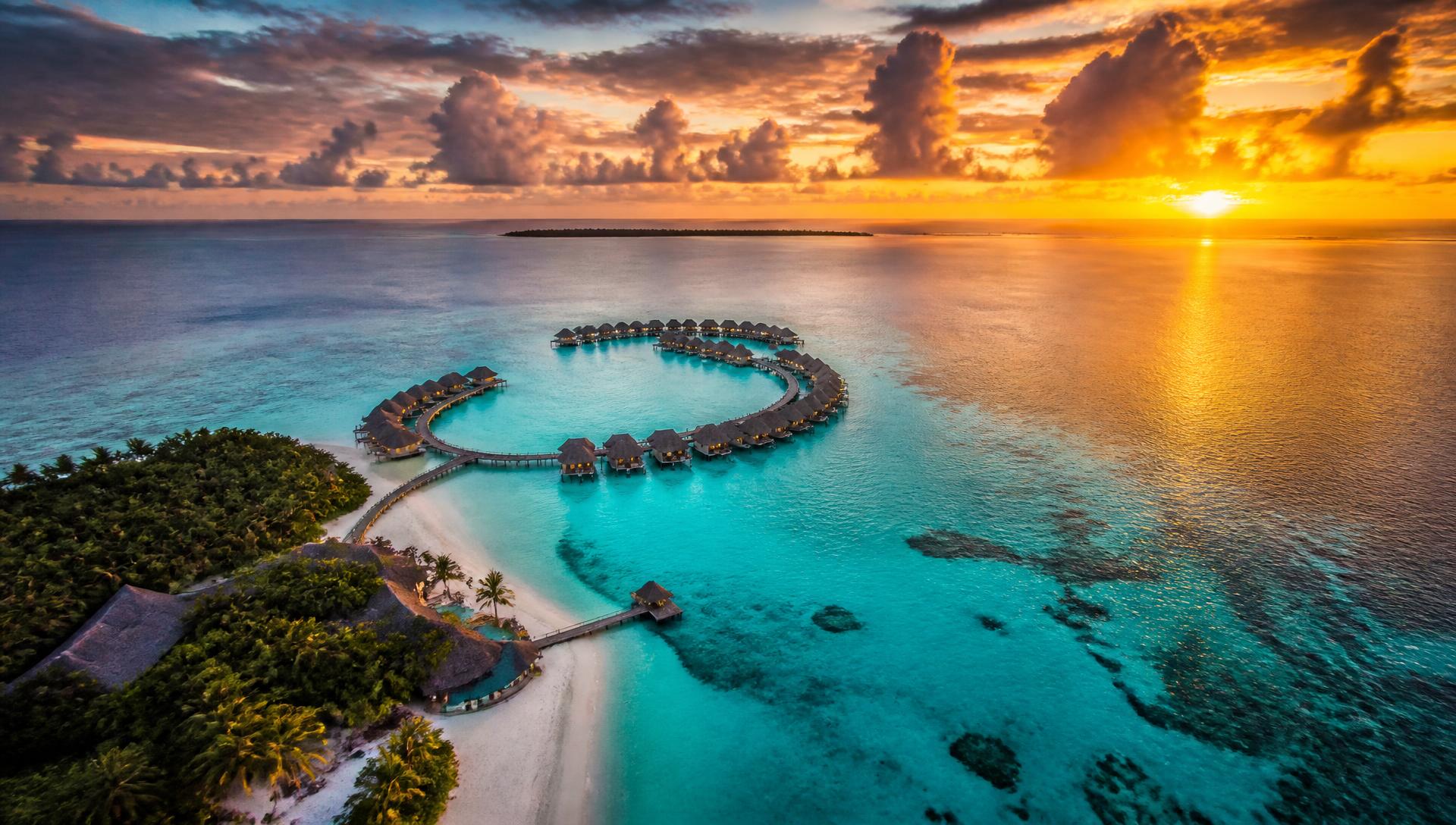 Overwater bungalows above a turquoise lagoon at sunset